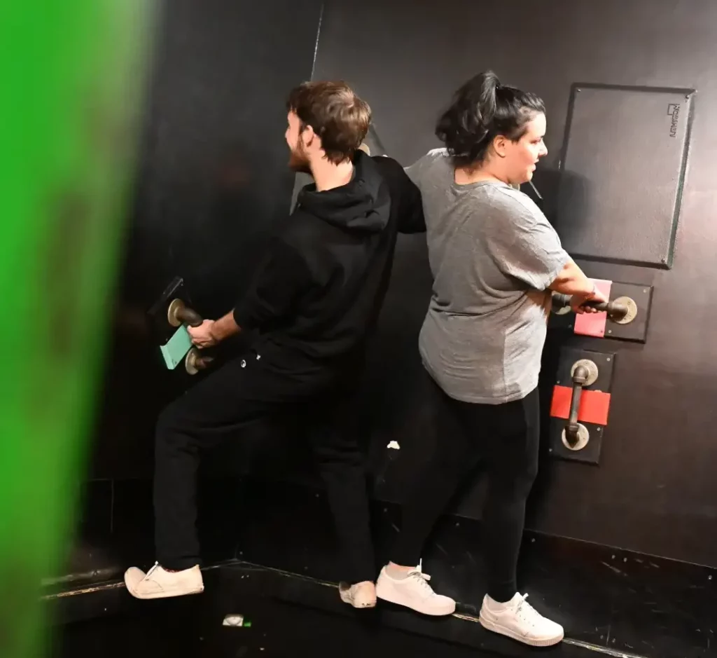 A man and woman hanging from bars on the wall