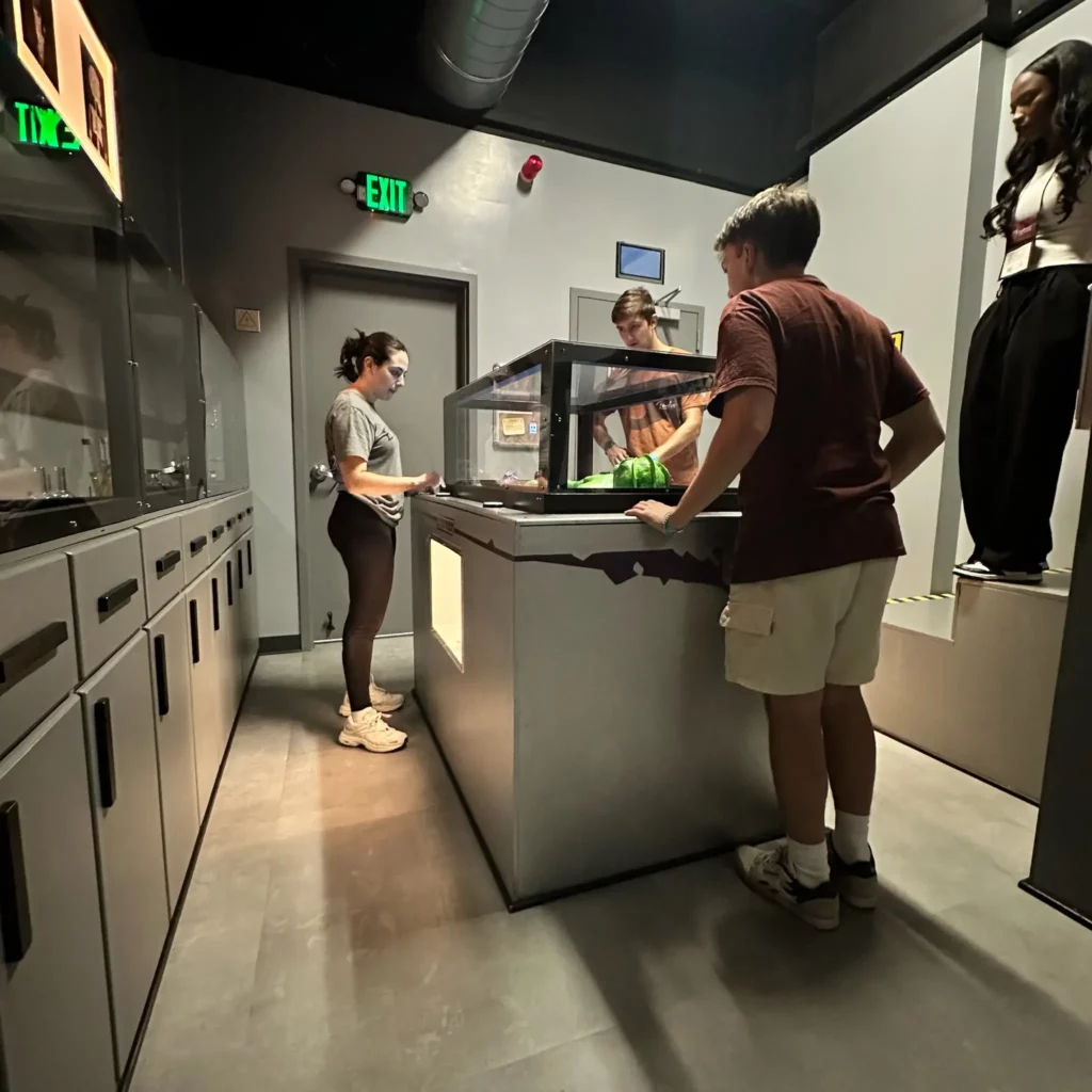 A group of people standing in front of a glass box with an alien in it