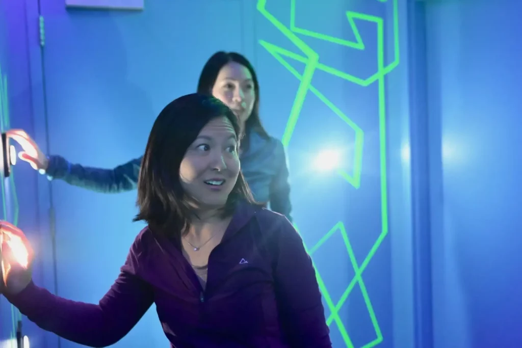 Two people reaching for an illuminated button