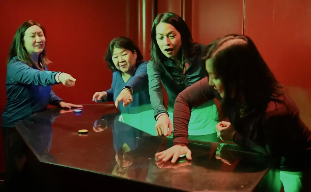 Four people hitting a green button