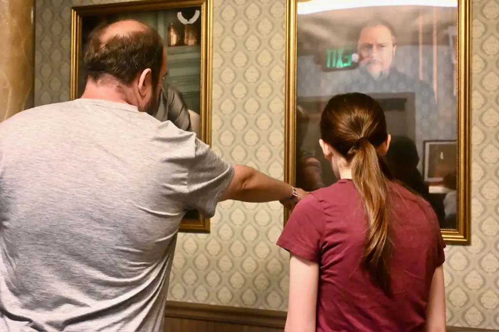 Two people pointing at a painting of a man